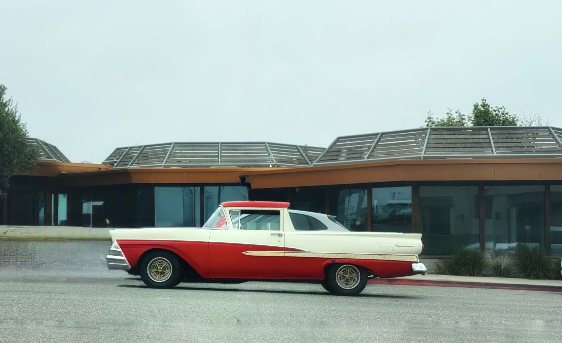 Vintage Ford parked against modern glass in Los Angeles